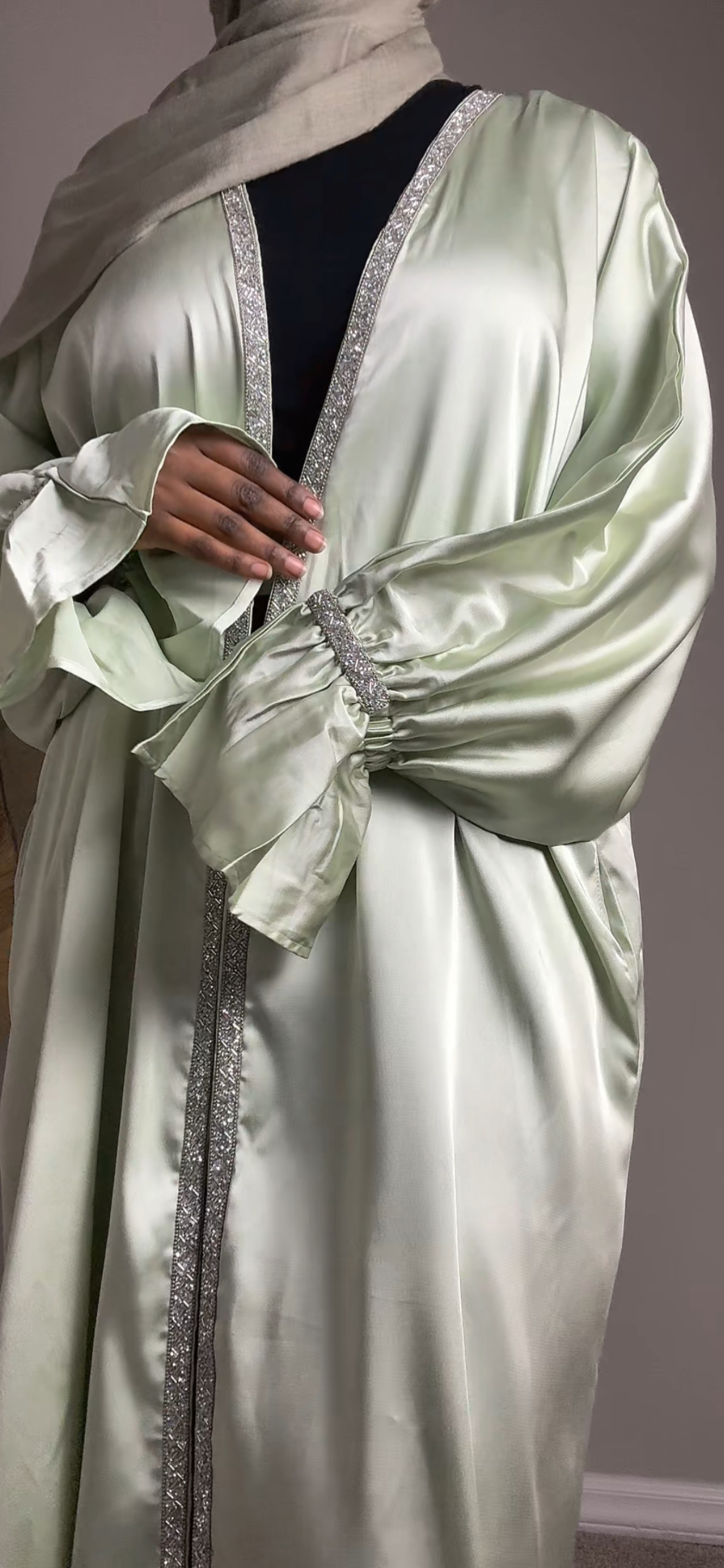 Light green abaya with intricate detailing on a plain background